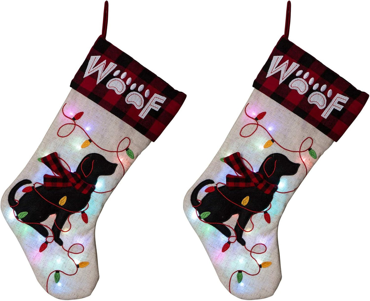 Pair of Glitzhome LED dog Christmas stockings – cream linen with black dog silhouette, red plaid "WOOF" cuff, and light-up embroidered string lights
