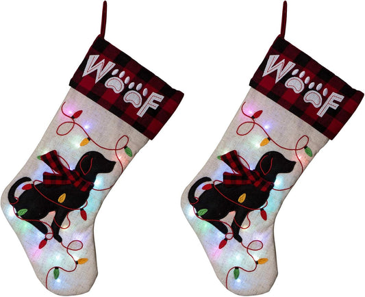 Pair of Glitzhome LED dog Christmas stockings – cream linen with black dog silhouette, red plaid "WOOF" cuff, and light-up embroidered string lights